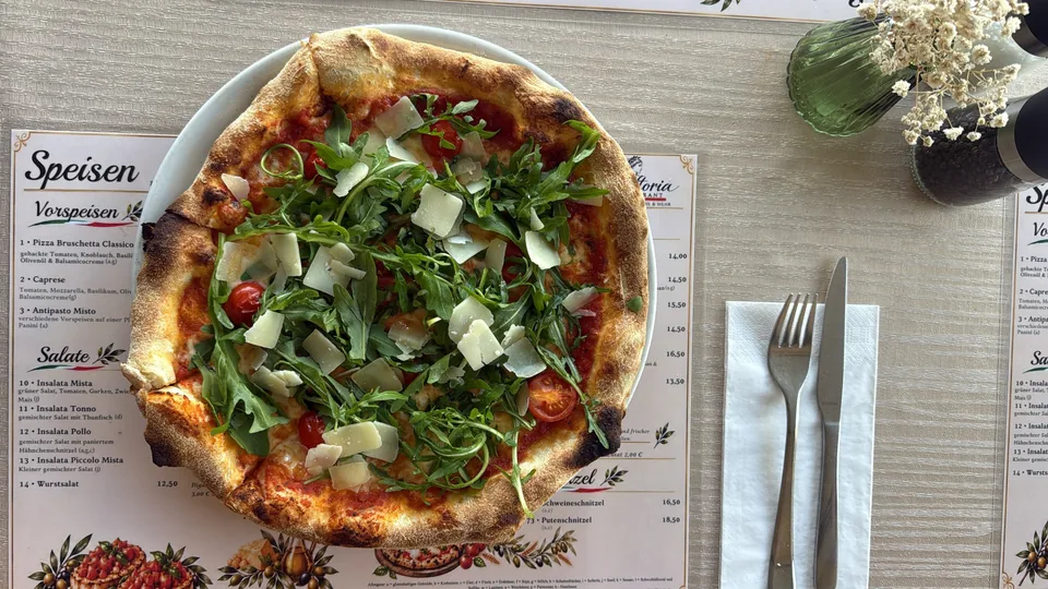 Frisch gebackene Pizza mit Rucola und Parmesan